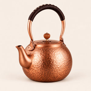 Auren hammered copper teapot with wrapped handle on a plain background