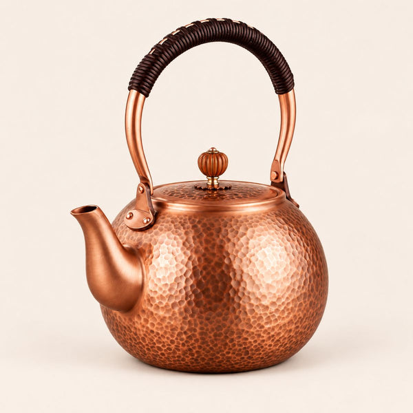 Auren hammered copper teapot with wrapped handle on a plain background