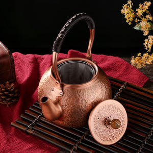 Auren copper teapot on a bamboo mat with its hammered lid beside it