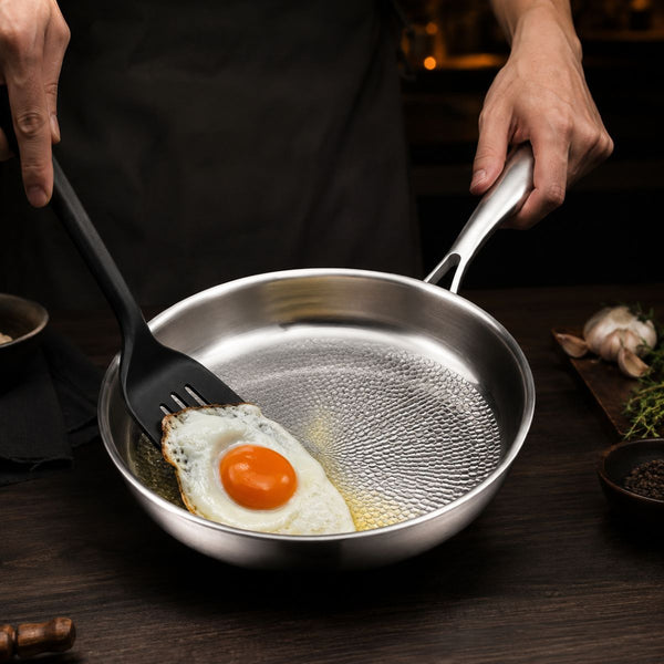 Fried egg lifted with a spatula from the hammered titanium frying pan