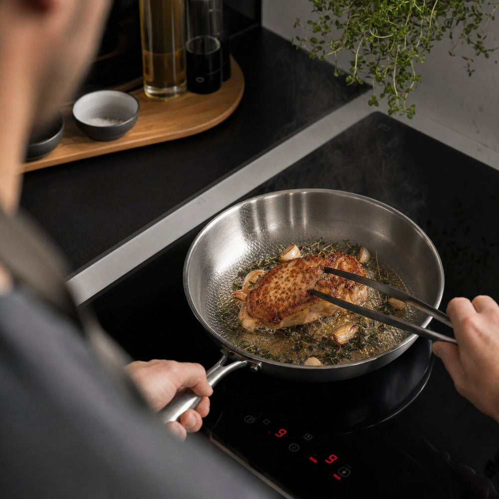 Hammered titanium frying pan with long steel handle on a wooden cutting board