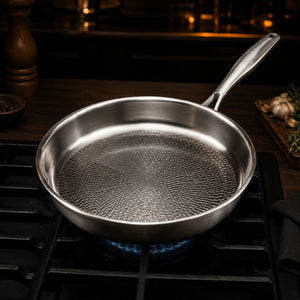 Empty hammered titanium frying pan heating over a gas burner