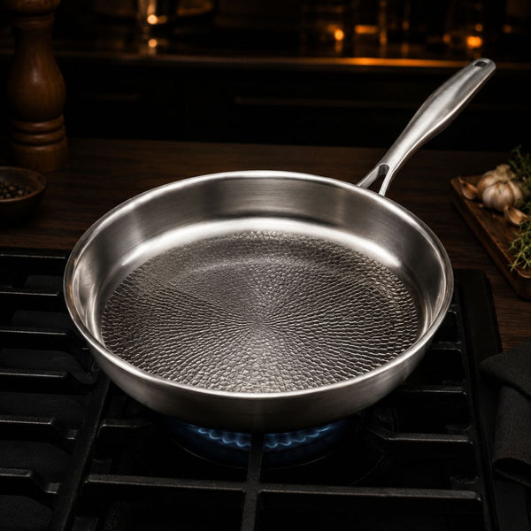 Empty hammered titanium frying pan heating over a gas burner