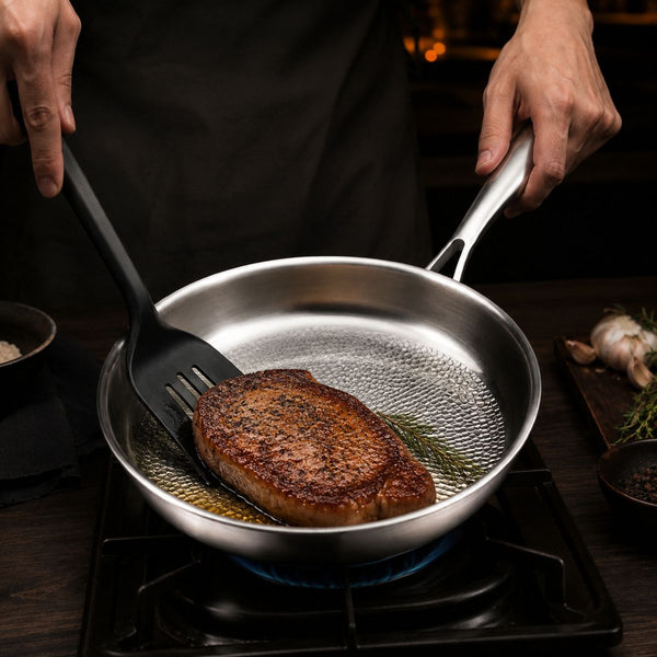 Steak searing over a gas flame in the hammered titanium frying pan
