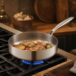Chicken and potatoes cooking in the high-wall titanium pan on a gas burner