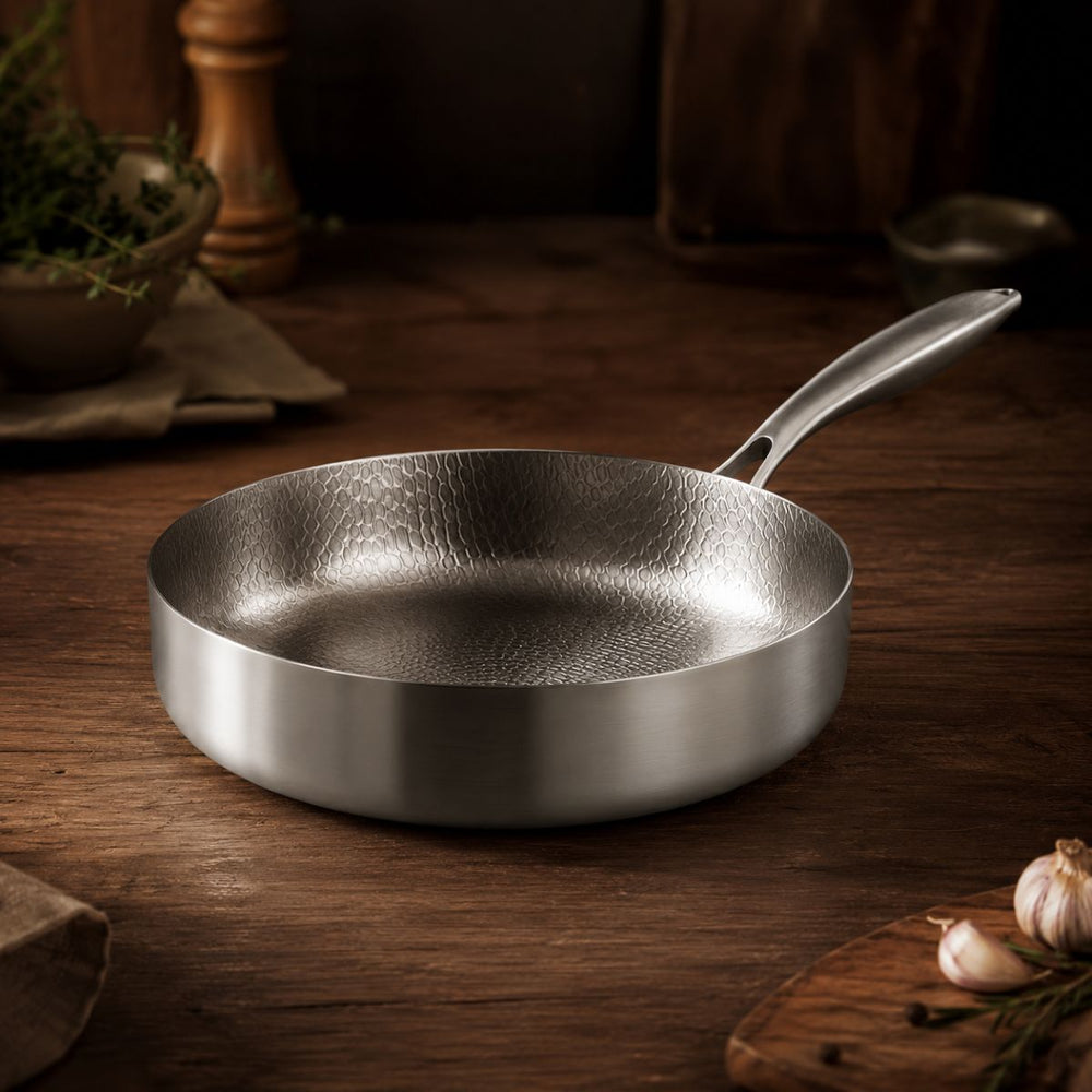 Hammered titanium deep frying pan with high walls on a wooden counter