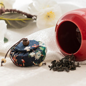 Close-up of the red porcelain tea caddy beside loose tea leaves
