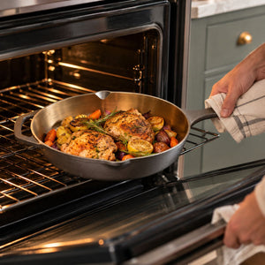 Putting the Kazan cast iron skillet with roast chicken and vegetables into the oven