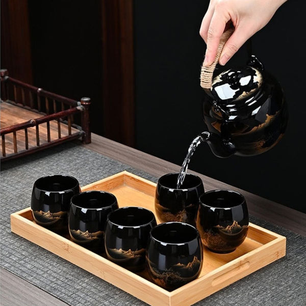 Tea poured from the Kumo black ceramic teapot into cups on the bamboo tray