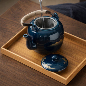 Water poured into the Kumo deep blue ceramic teapot through its stainless steel strainer