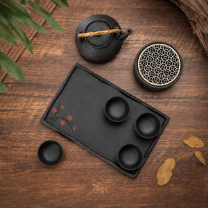 Top view of the Nagi matte black tea set with teapot, warmer, four cups and plum blossom tray