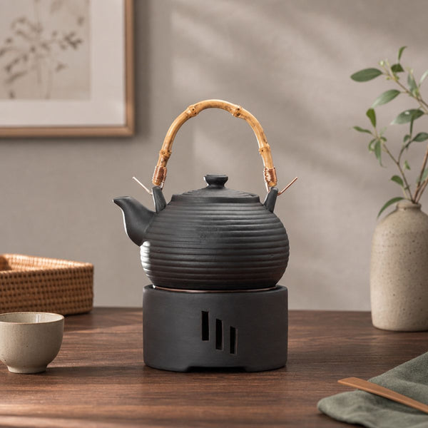 Nagi matte black clay teapot resting on its candle warmer