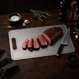 Sliced roast beef resting on the pure titanium cutting board with a knife