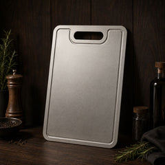 Pure titanium cutting board standing upright on a dark wooden counter