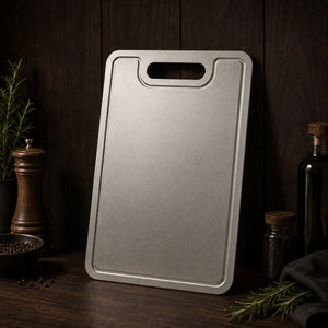 Pure titanium cutting board standing upright on a dark wooden counter