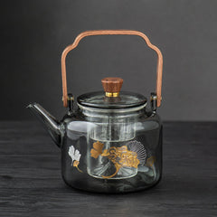 Reika smoked glass teapot with walnut handle and gold ginkgo motif on dark wood