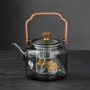 Reika smoked glass teapot with walnut handle and gold ginkgo motif on dark wood