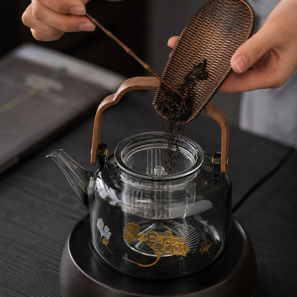 Reika smoked glass teapot with walnut handle and gold ginkgo motif on dark wood