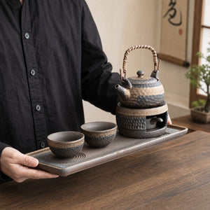 Person carrying the Renji pottery tea set on its serving tray
