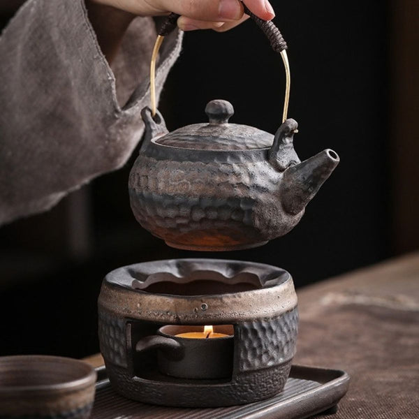 Renji pottery teapot lifted above its lit candle warmer