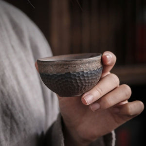 Hand holding a Renji textured pottery tea cup