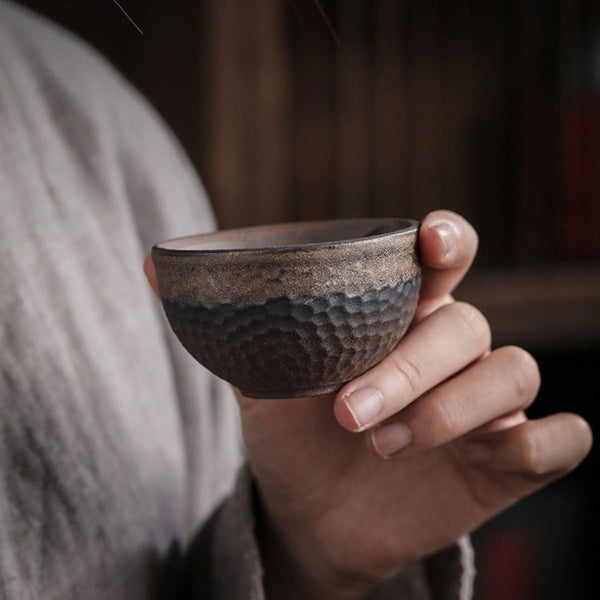 Hand holding a Renji textured pottery tea cup
