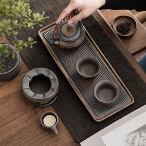 Top view of the Renji teapot and two cups on the serving tray with the warmer beside it