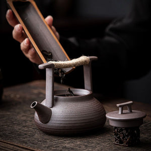 Adding loose-leaf tea to the Sumi ceramic teapot from a bamboo tea scoop