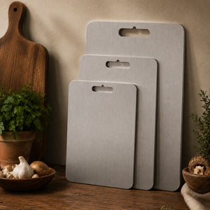 Three sizes of the titanium cutting board standing against a kitchen wall