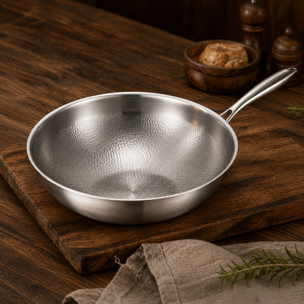 Hammered titanium wok pan with long steel handle on a wooden board