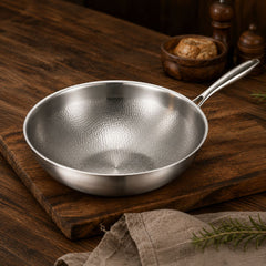 Hammered titanium wok pan with long steel handle on a wooden board