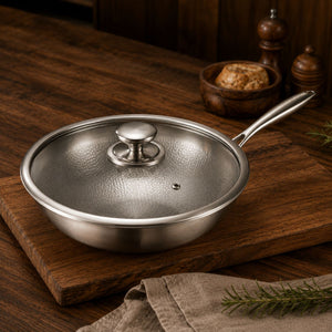 Titanium wok pan covered with its tempered glass lid on a wooden board