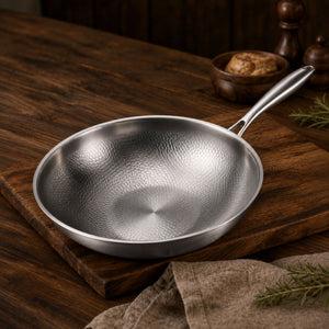 Empty titanium wok on a wooden board, hammered cooking surface visible