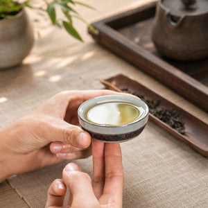 Hands holding a Yunlong ceramic tea cup with ice crack glaze